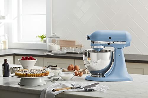 Blue stand mixer on kitchen counter with baking ingredients.