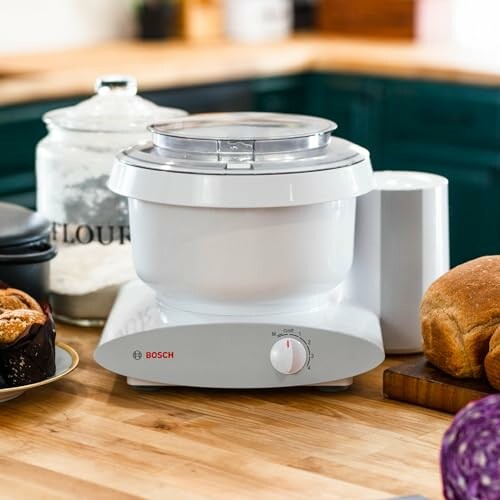 Bosch kitchen mixer on a wooden countertop with bread and flour.