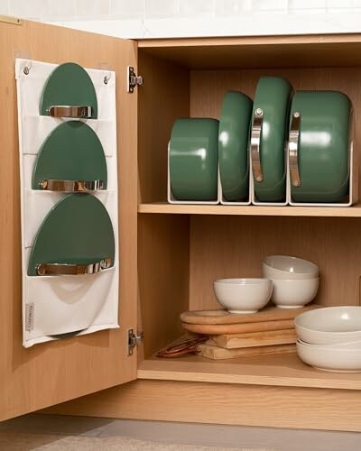 Neatly organized kitchen cabinet with green cookware and bowls.